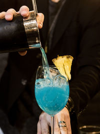 Close-up of bartender pouring cocktail in glass at nightclub