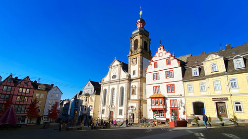 Low angle view of buildings in city against clear blue sky