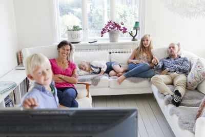 Family with three kids watching tv on sofa