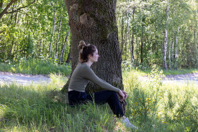 Side view of young woman standing in forest