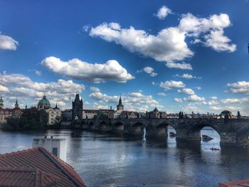 Bridge over river by buildings against sky