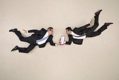 Friends lying on floor against white background