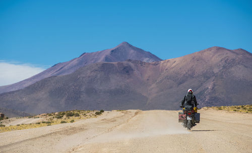 Rear view of man riding motorcycle on mountain road