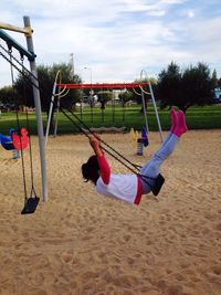 Side view of girl playing at swing in playground