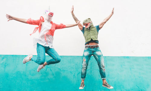 Friends wearing masks while jumping against wall