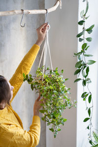 Woman holding potted plant hanging against wall