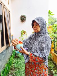 Woman looking away while standing against plants