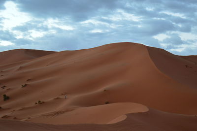 Scenic view of desert against cloudy sky