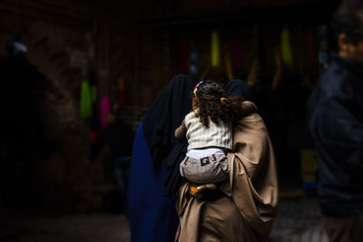 Mother carrying daughter at market in city