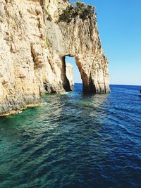 Rock formation by sea against blue sky