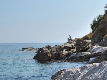 Rock formation in sea against clear sky