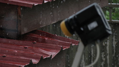 Cropped image of satellite dish against roof in rain