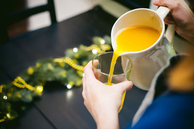 Cropped hands of woman pouring juice in drinking glass