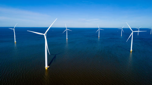 Wind turbines on field against sky