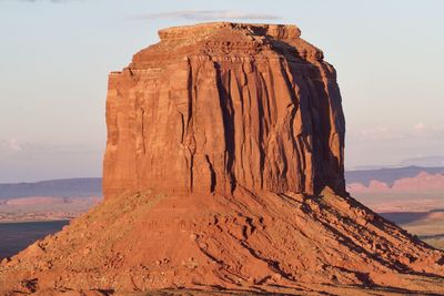 Setting sun casts golden light on a sandstone butte in monument valley