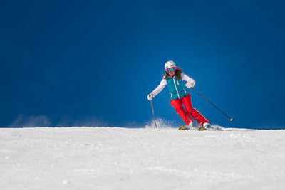 Person skiing on snowy mountain against blue sky