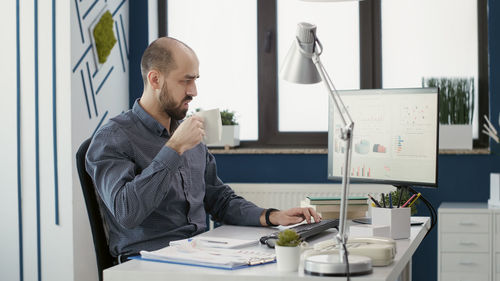 Side view of woman using mobile phone while sitting on table