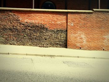 Shadow of brick wall on footpath
