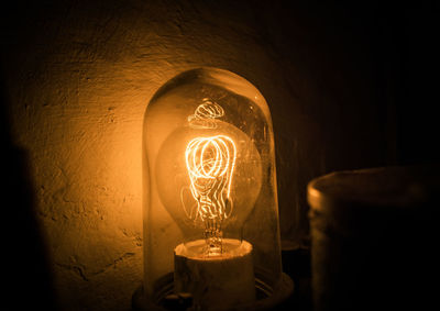 Close-up of illuminated light bulb against wall