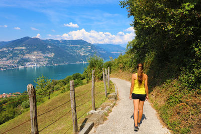 Rear view of woman standing on mountain by plants