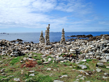 Stack of rocks by sea against sky