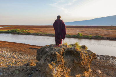 Rear view of a man wearing masai clothes standing on a scenic view point at lake natron, tanzania