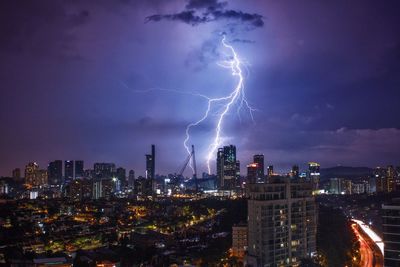 Lightning in city against sky at night