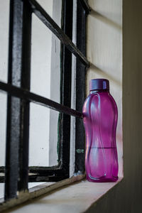 Close-up of purple bottle on window sill at home