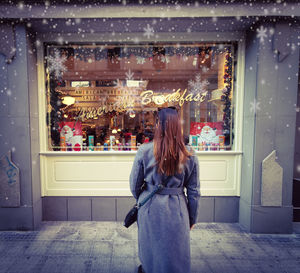 Rear view of woman standing by store on footpath