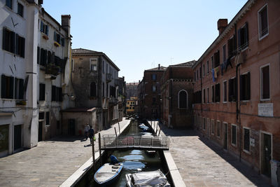 Canal amidst buildings in city against clear sky