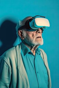 Side view of senior grandfather in virtual headset glasses against blue background. ai generated