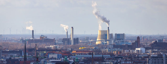 Smoke emitting from factory against sky