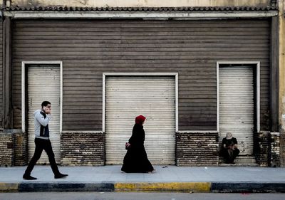 Side view of people walking against building