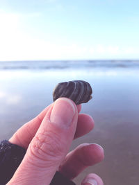 Midsection of person holding sea against sky