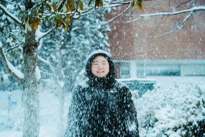 Portrait of smiling young woman standing against trees