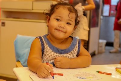 Portrait of cute girl holding table at home