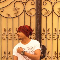 Young man looking away while standing against wall