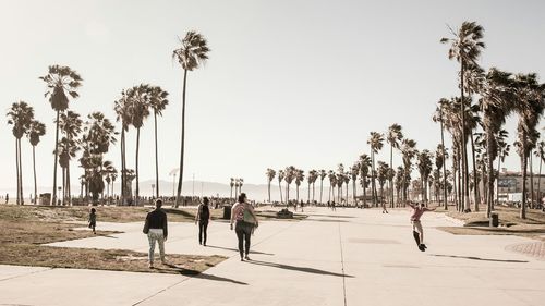 People walking on pedestrian walkway against clear sky