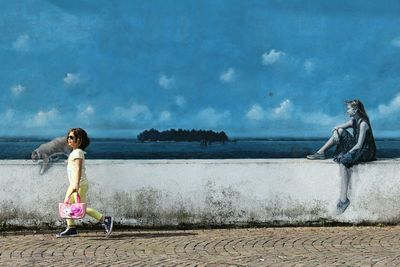 Girl standing by sea against sky