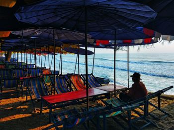 Rear view of man sitting on chair at beach