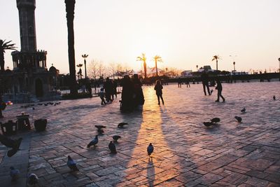 View of people on shore against sky during sunset