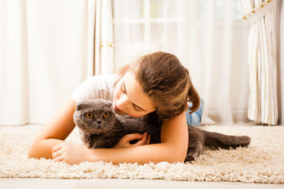 Young woman with cat lying on bed at home