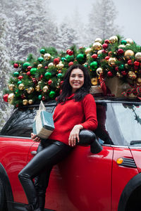 Portrait of woman standing by car during christmas