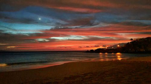 Scenic view of sea against dramatic sky during sunset