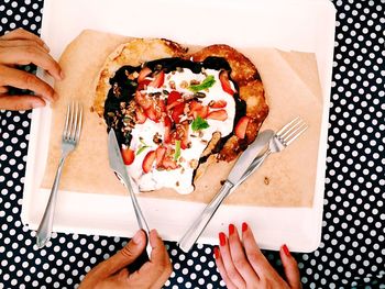 Cropped hands of friends with pancake on table