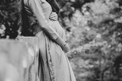 Midsection of pregnant woman with hands on stomach standing outdoors