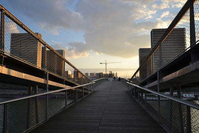 Footbridge over city against sky