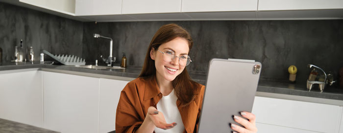 Portrait of young woman using mobile phone while sitting at home