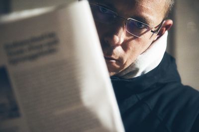 Adult man disturbed reading the newspaper and looking at camera