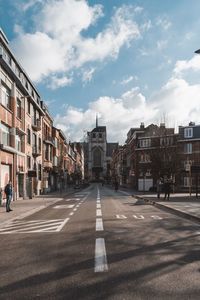 Road by buildings against sky in city